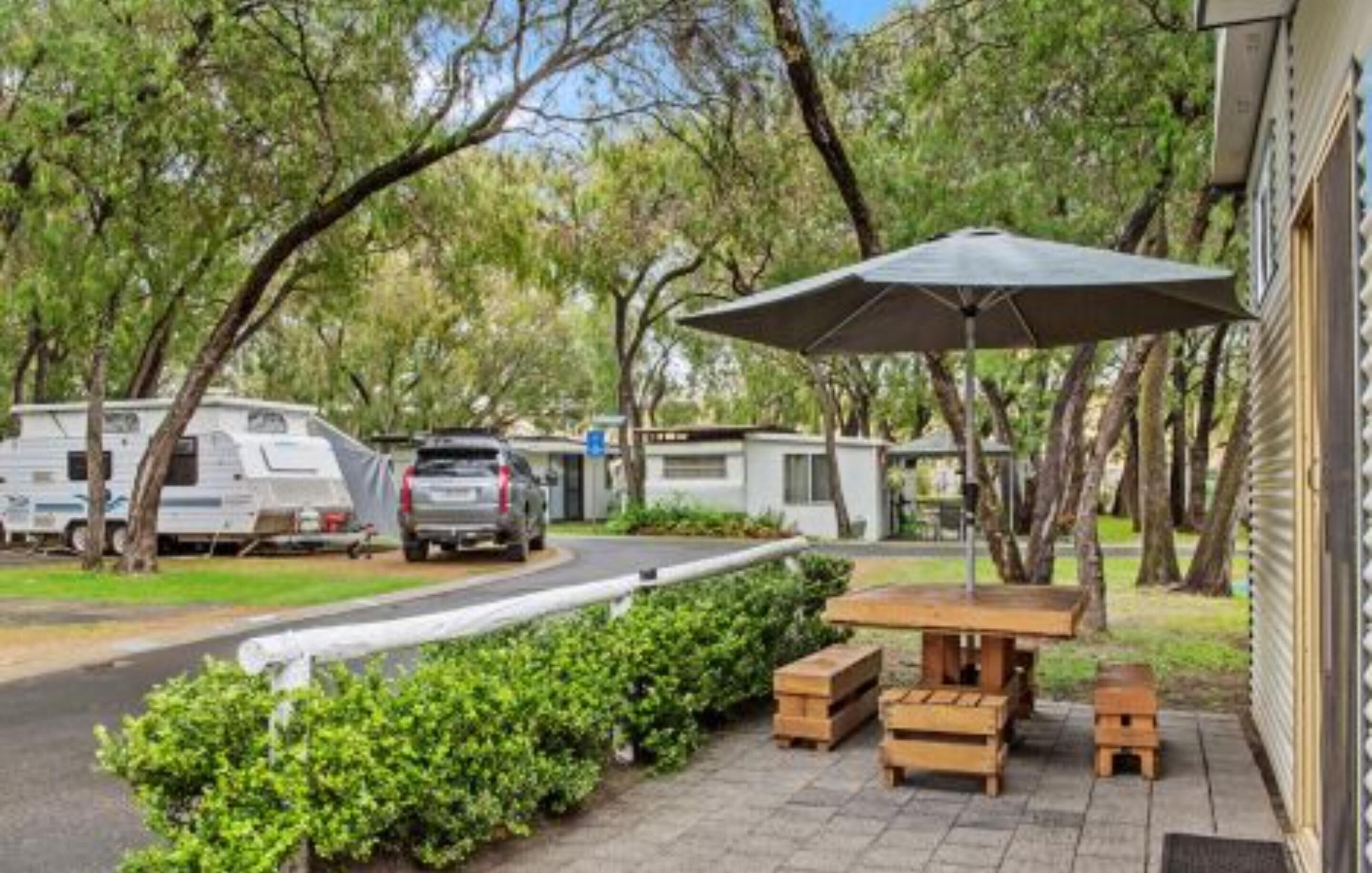 A campsite with RVs, a picnic table, and a covered area.