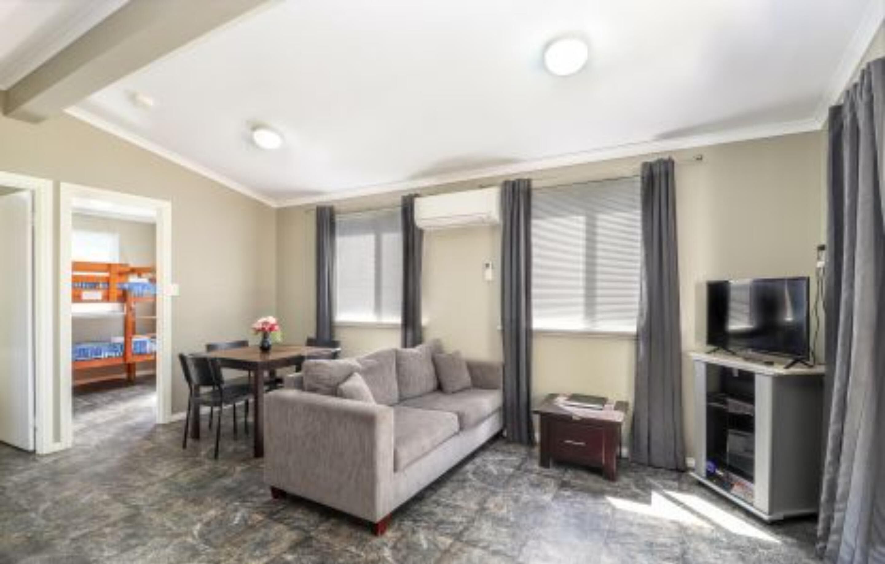 Un salon comprenant un canapé, un téléviseur et un coin repas avec une table et des chaises.