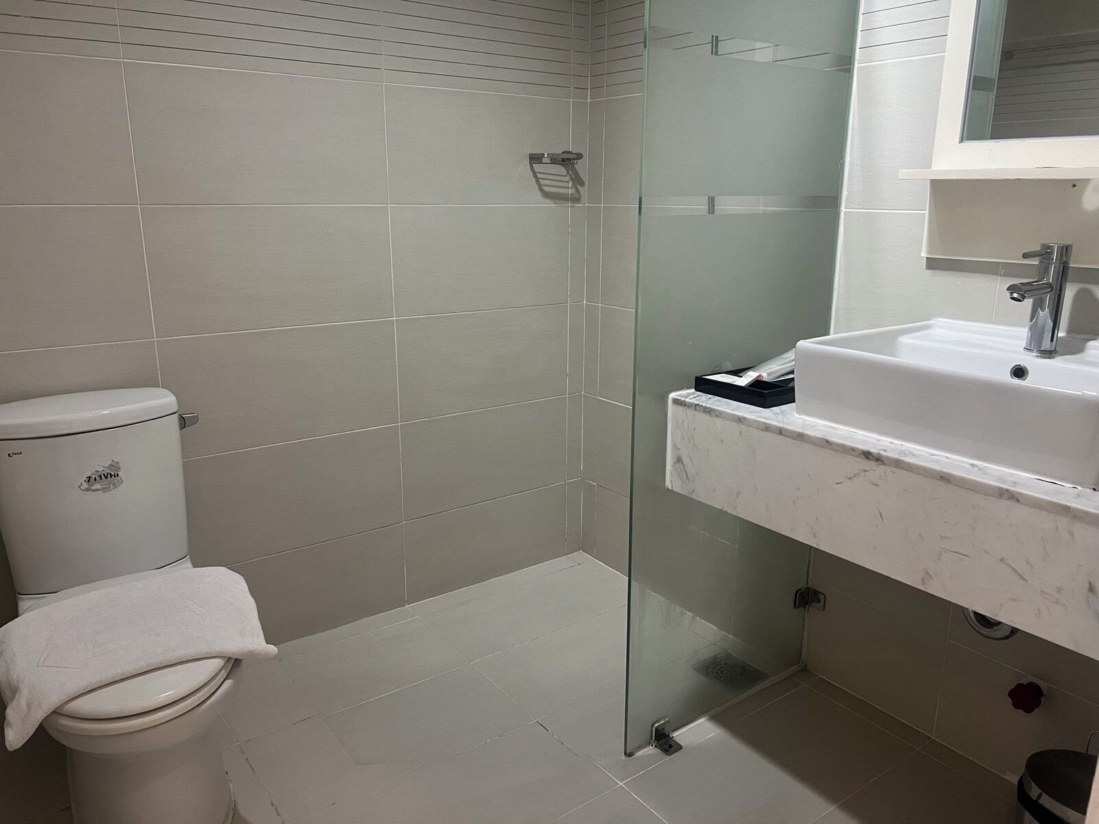 Une salle de bain comprenant des toilettes, une douche à parois de verre et un lavabo avec un miroir au-dessus.