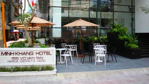 The exterior of the MNHKHANG HOTEL with outdoor seating and a glass facade.