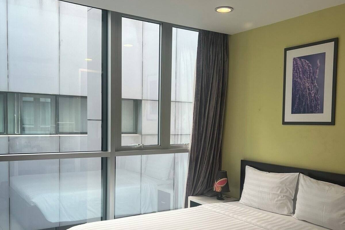 Habitación de hotel moderna con una cama grande, una mesita de noche, una lámpara y un cuadro en la pared.