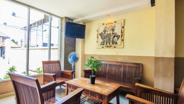 A room with a wooden table and chairs, a large window, a wall-mounted TV, and a framed picture. - Sanur Ayu Hotel (Denpasar)