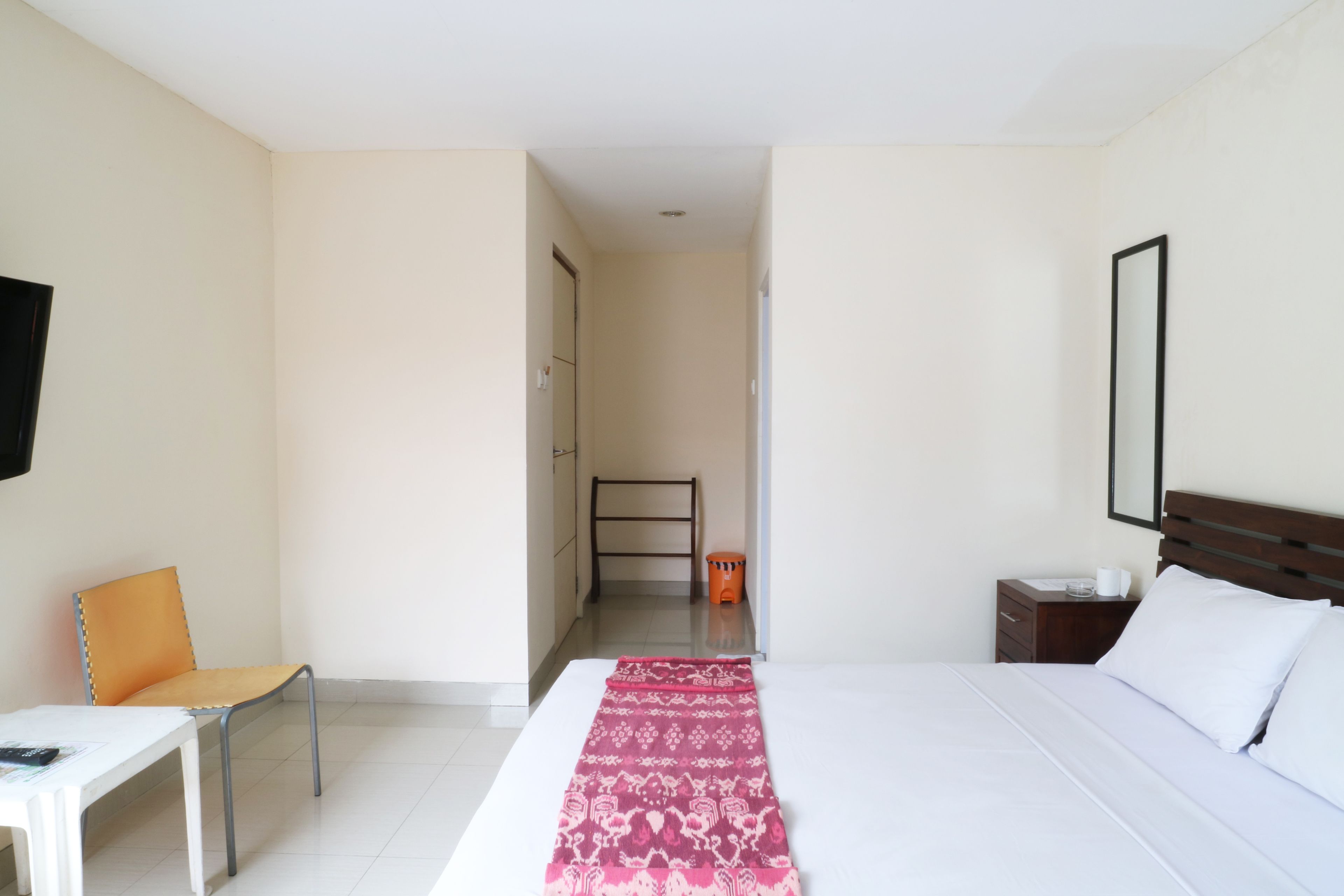 Una habitación de hotel con una cama, una silla, una mesita de noche y un televisor en la pared.
