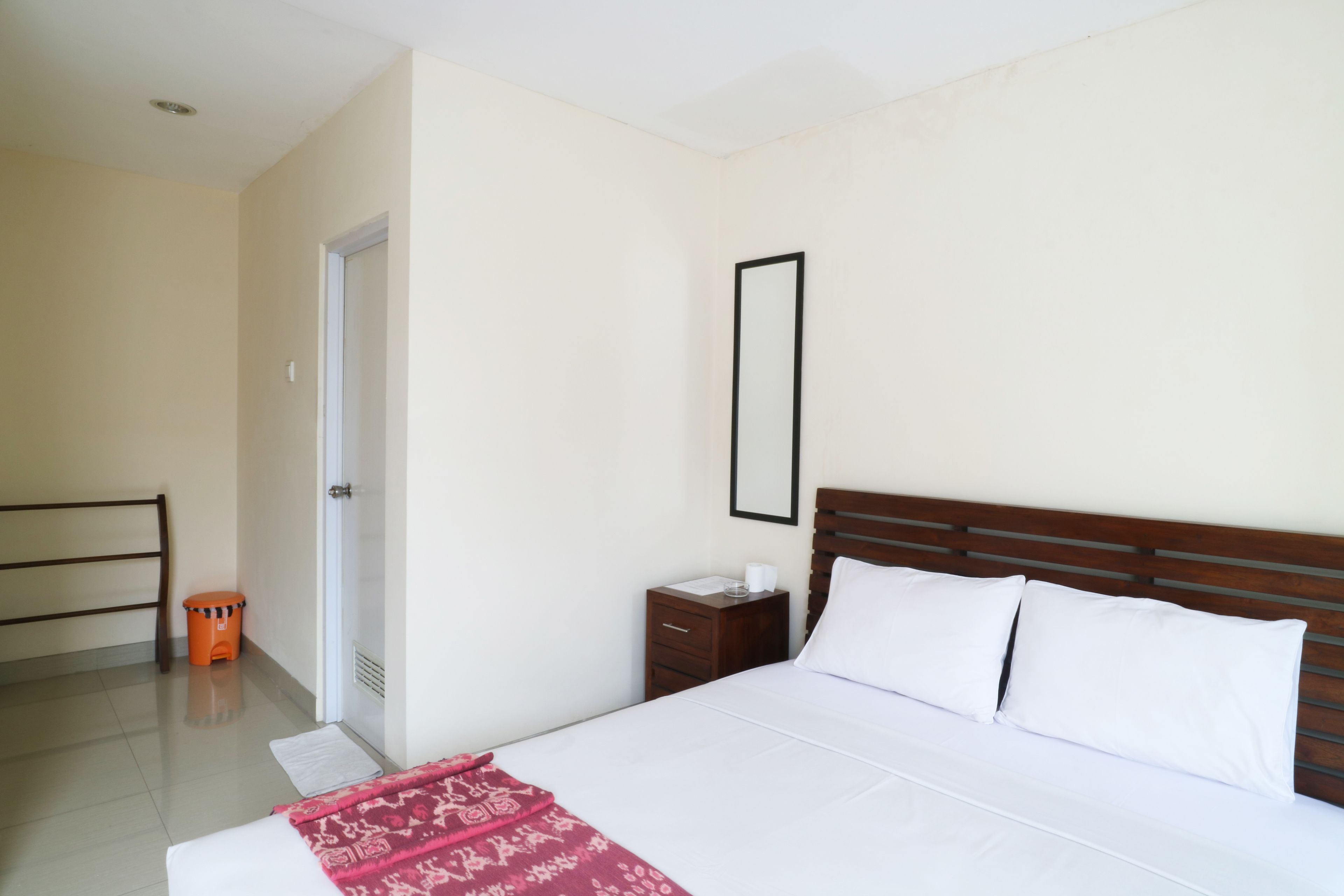 Une chambre à coucher avec un lit, une table de chevet, un miroir et une porte.