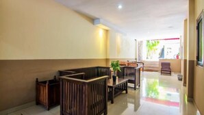 A hallway with wooden benches, a table with a plant, and a view of a staircase leading outside. - Sanur Ayu Hotel (Denpasar)