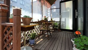A wooden deck with potted plants, a wooden chair, and a table. - Sapporo Inn NADA - Hostel (Sapporo)