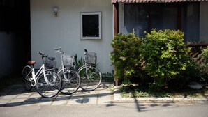 Two bicycles parked outside a building with a window and a small door. - Sapporo Inn NADA - Hostel (Sapporo)