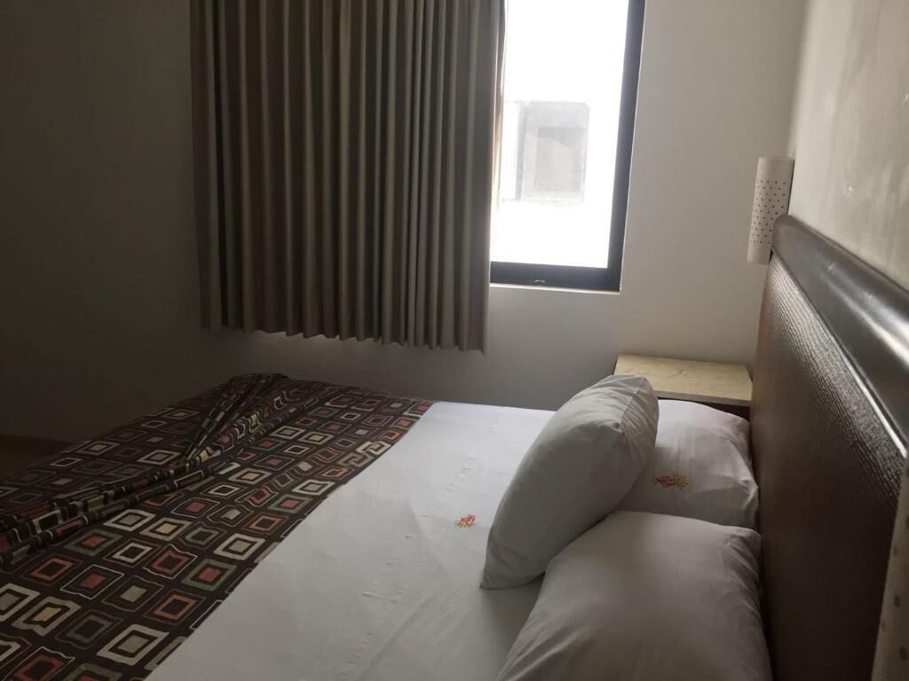 A bedroom with a bed, a window with curtains, and a nightstand.