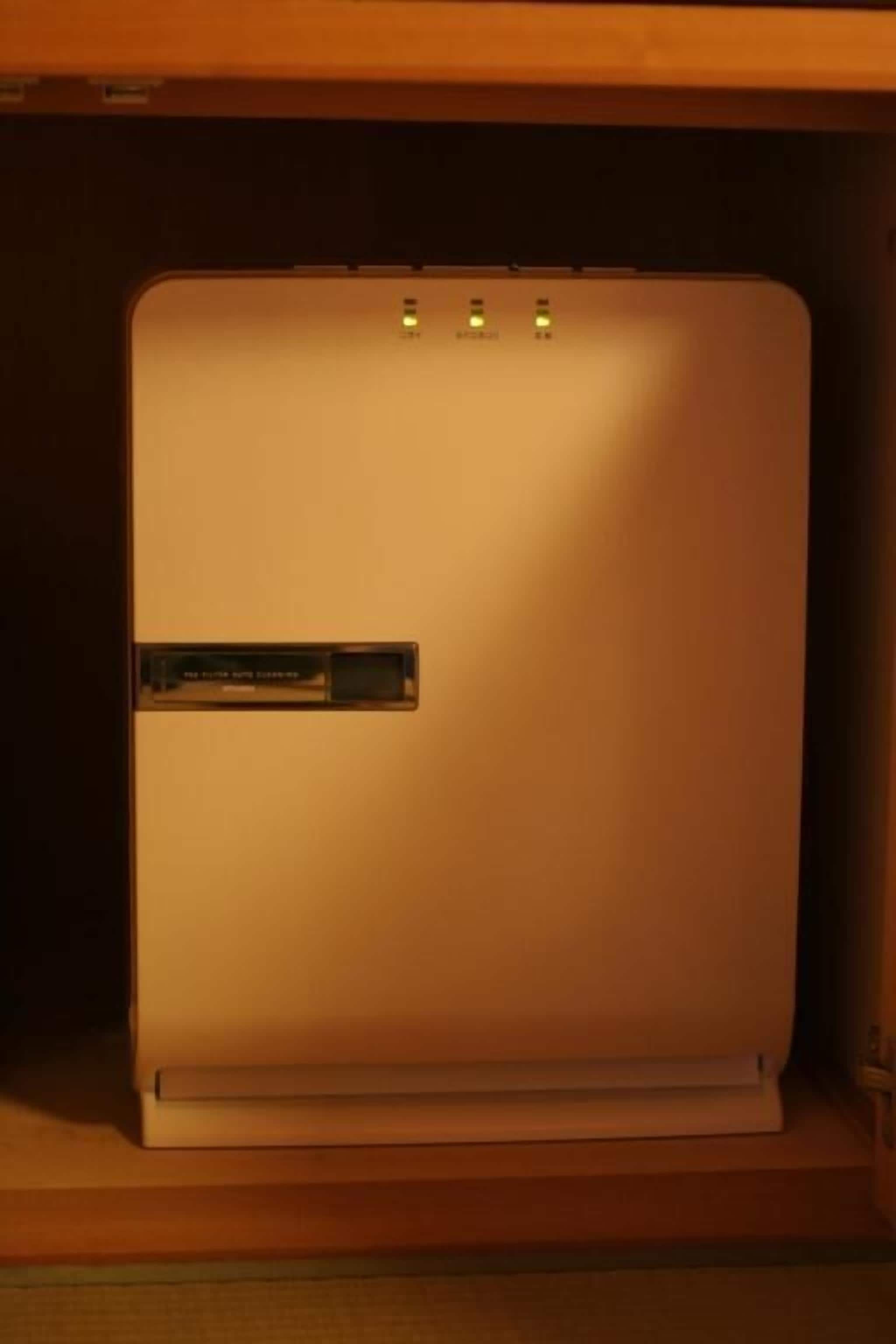 A white refrigerator with a control panel and a handle, placed inside a wooden cabinet.