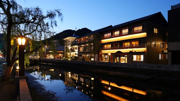 A multi-story hotel with illuminated balconies and a reflection in the water. - Kinosaki Onsen Ichidaya (Toyooka)