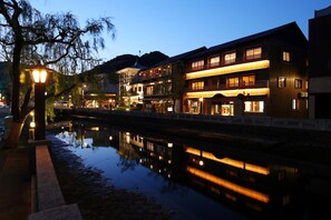 A multi-story hotel with illuminated balconies and a reflection in the water. - Kinosaki Onsen Ichidaya (Toyooka)