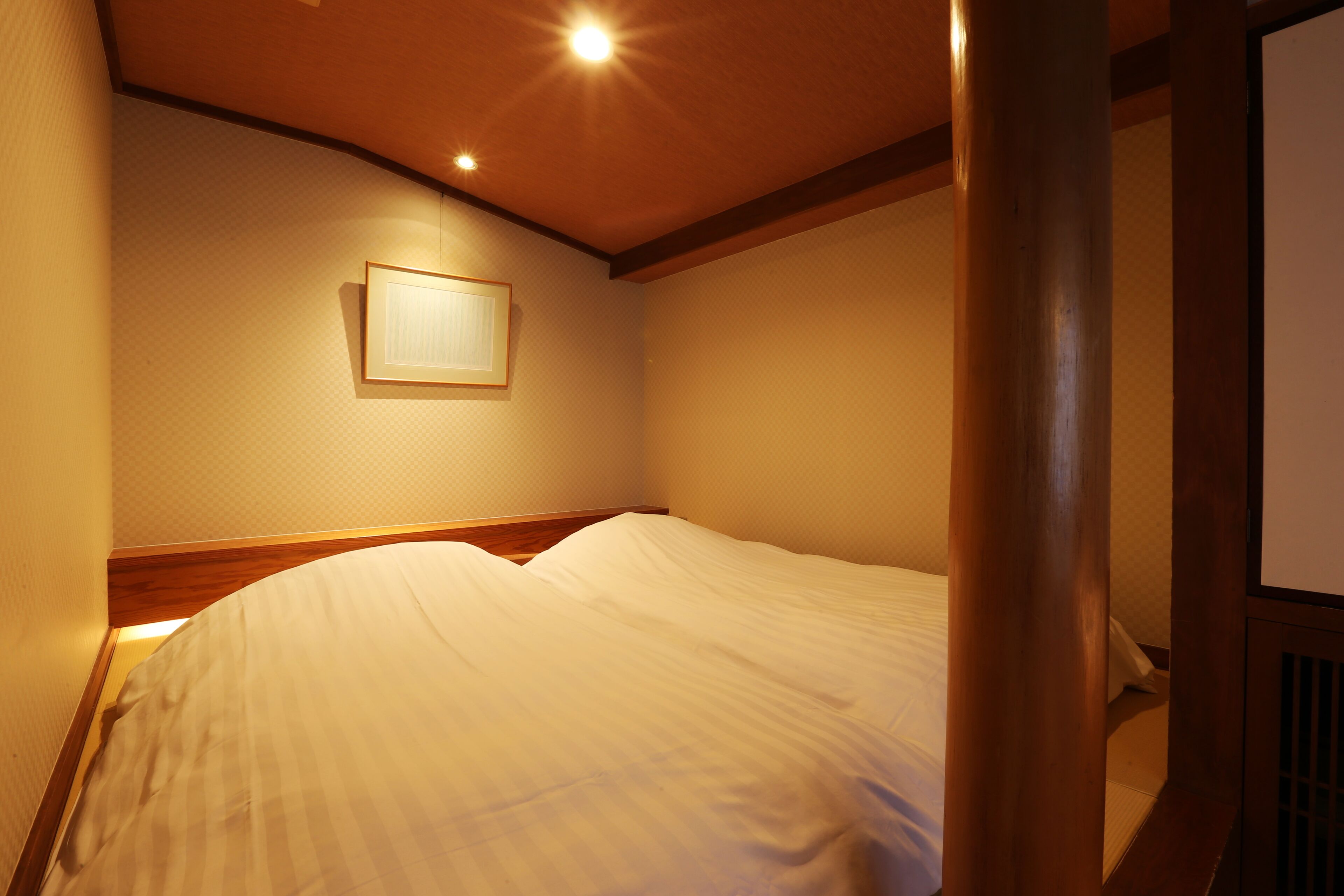 Una cama bien hecha en una habitación de hotel con cabecera de madera y un cuadro en la pared.