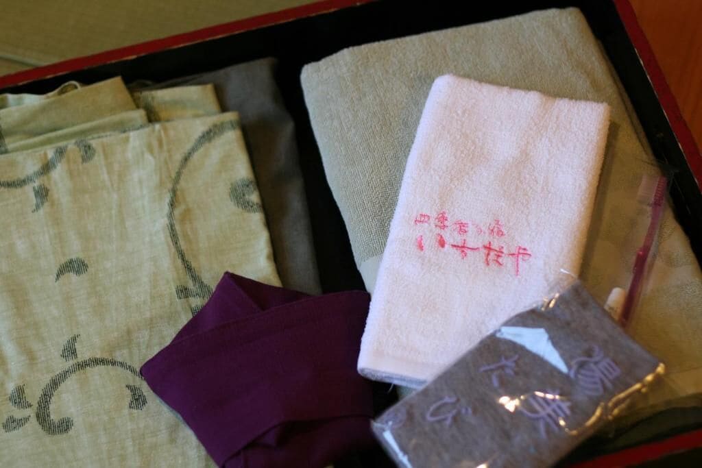 A neatly arranged set of towels and a small bag in a box.