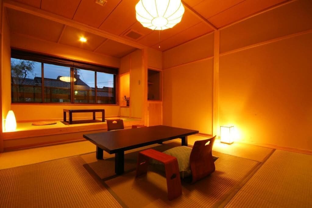 Una habitación japonesa tradicional con suelo de tatami, una mesa baja y cojines.