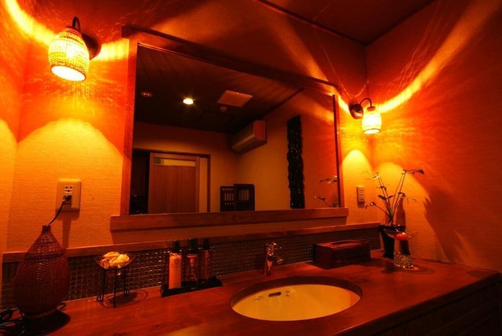 A bathroom with a wooden vanity, a large mirror, and two wall-mounted lights.