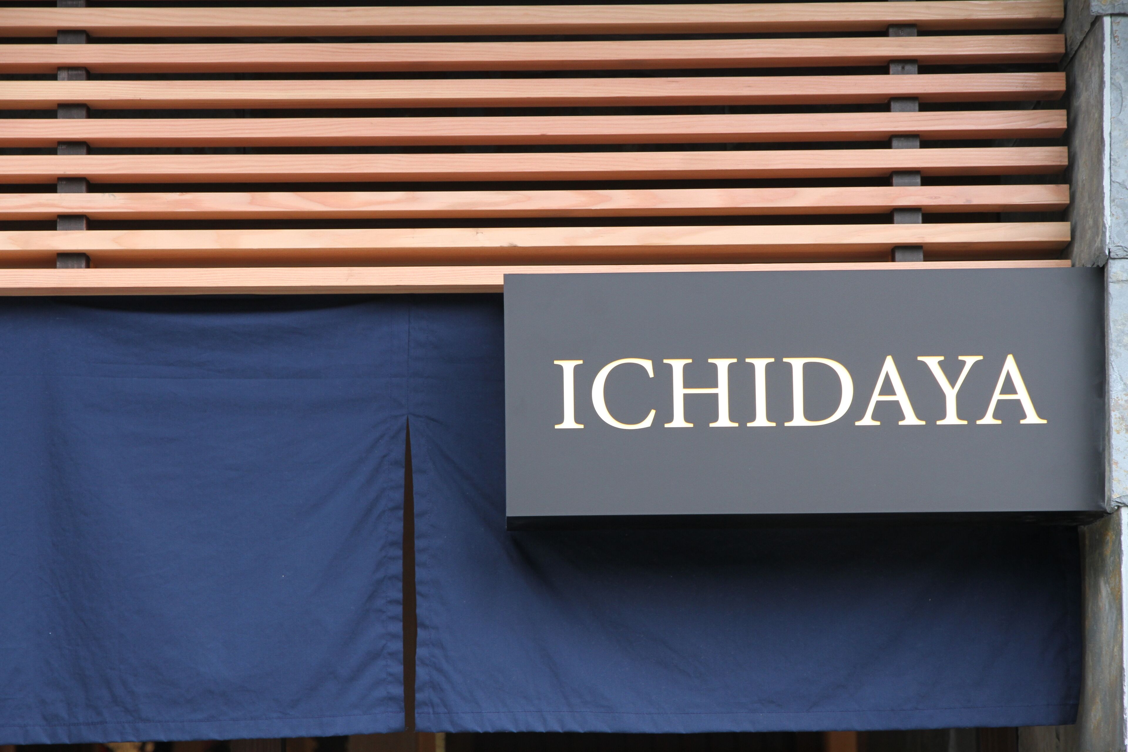A sign with the name "ICHIDAYA" on a building facade.