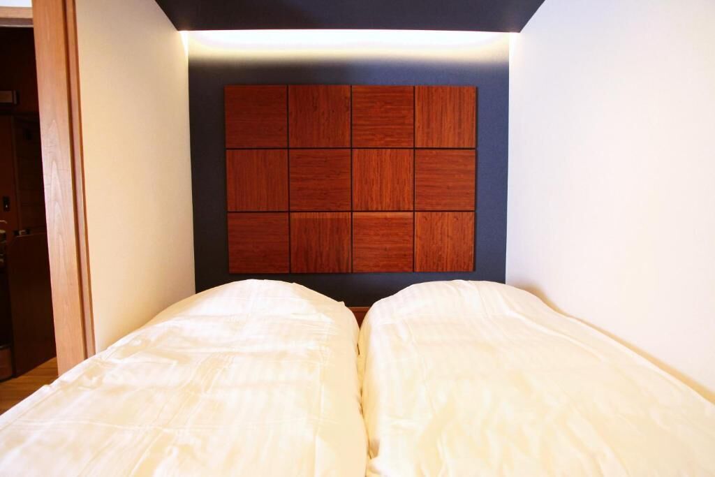 Une pièce avec un lit, une tête de lit en bois et une porte.