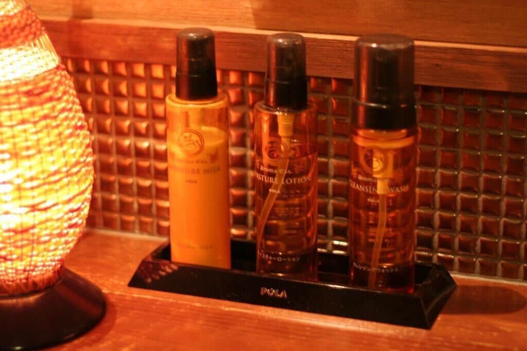 A bathroom vanity with a black soap dish holding three bottles of body care products.