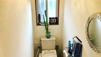 A compact bathroom with a toilet, bidet, and a small window.