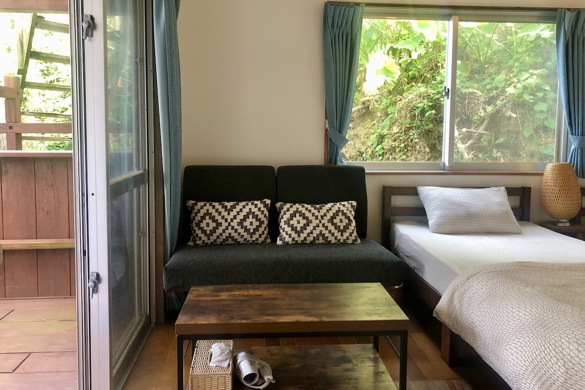 Um quarto com sofá, cama, mesa e janela com cortinas.