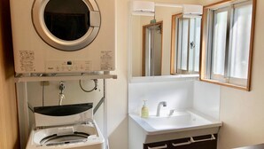 A compact bathroom with a washing machine, a sink, and a mirror. - Life is a Journey - Hostel (Yomitan)