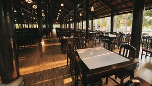 Un restaurante espacioso con techos altos, pisos de madera y numerosas mesas y sillas.