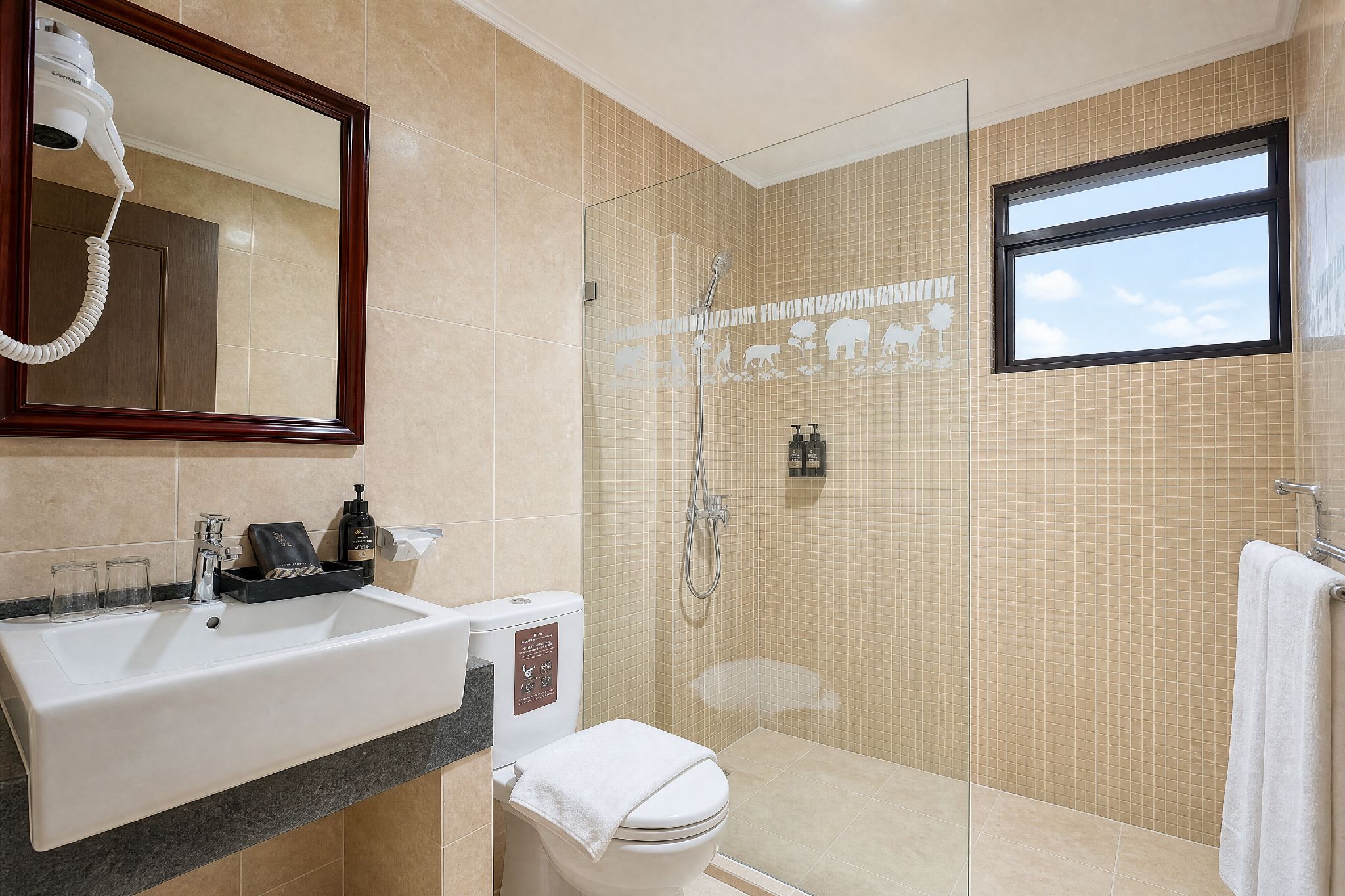 A bathroom with a sink, mirror, toilet, shower, and a window.