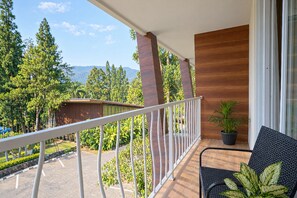Ein Balkon mit Blick auf eine gebirgige Landschaft, eine Holzwand und ein Blumentopf.