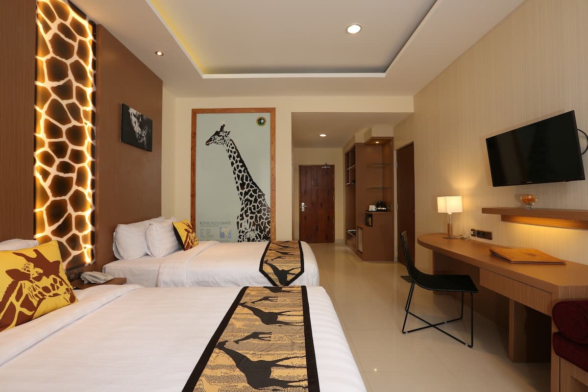 Une chambre d’hôtel avec deux lits, un bureau, une télévision et une décoration sur le thème des girafes.