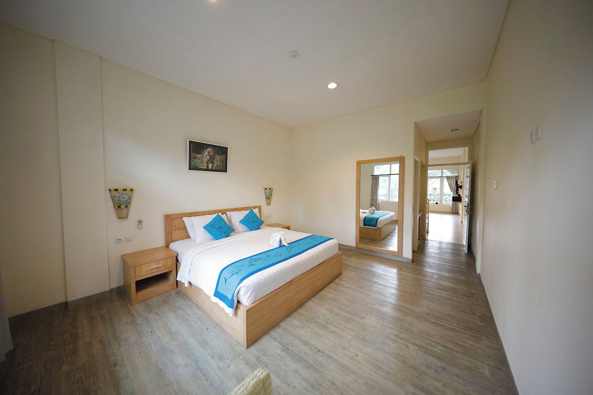 Une chambre à coucher avec un lit en bois, des murs blancs et un grand miroir.