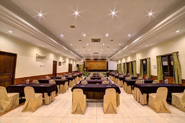 A conference room with multiple tables and chairs, equipped with projectors and screens.