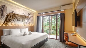 A hotel room with a large bed, a desk, a television, and a mural of a leopard.
