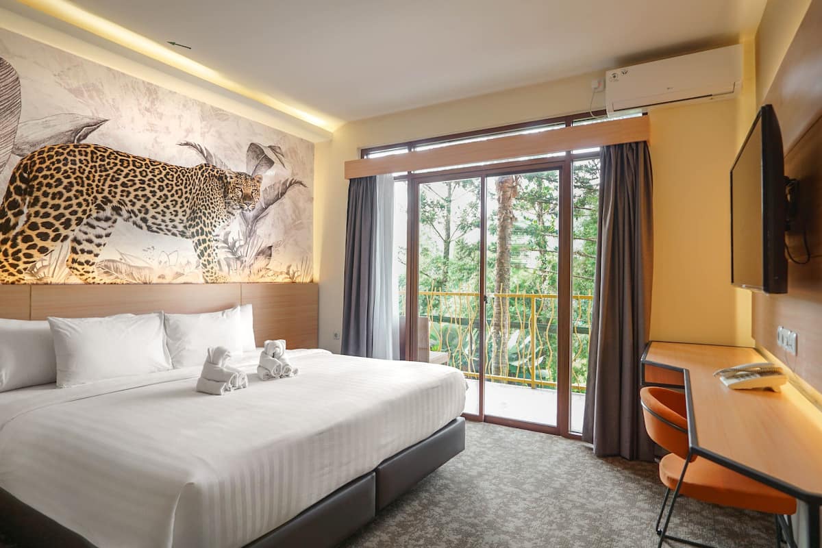 Une chambre d’hôtel avec un grand lit, un bureau, une télévision et une fresque représentant un léopard.