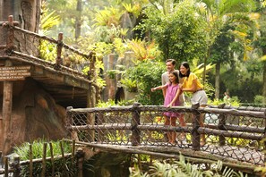 A rustic wooden bridge with a chain-link fence, surrounded by lush greenery and tropical plants. - Royal Safari Garden Resort & Convention (Cisarua)