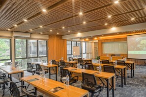 Une salle de conférence équipée de plusieurs tables, de chaises et d’un écran de présentation.