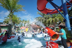 Een waterpark met een grote rode glijbaan en een waterpomp.