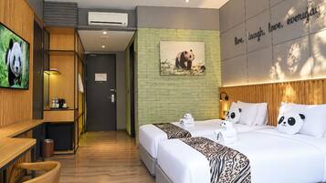 A hotel room with a bed, a desk, a TV, and a panda-themed wall decoration.