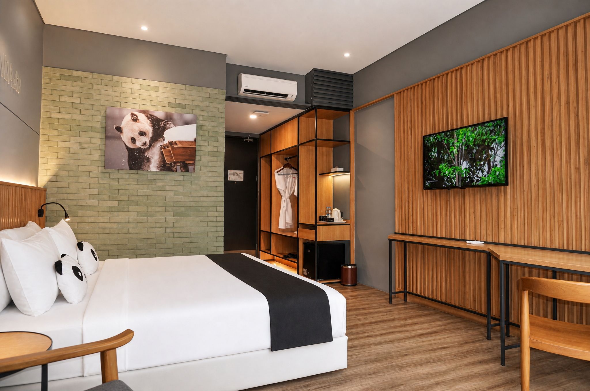 A modern hotel room with a bed, a desk, a TV, and a panda-themed artwork.
