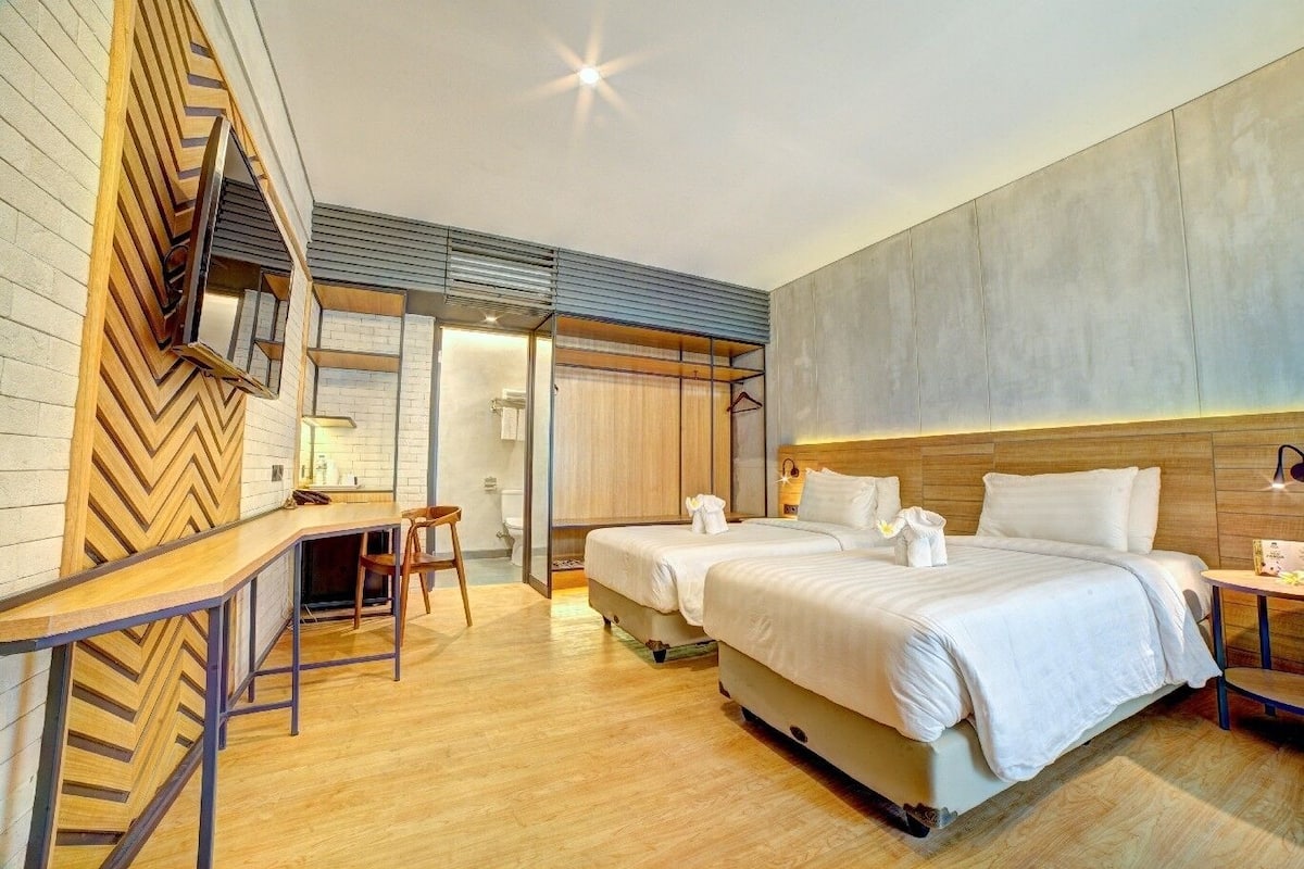 Une chambre d’hôtel avec deux lits, un bureau et un espace douche.