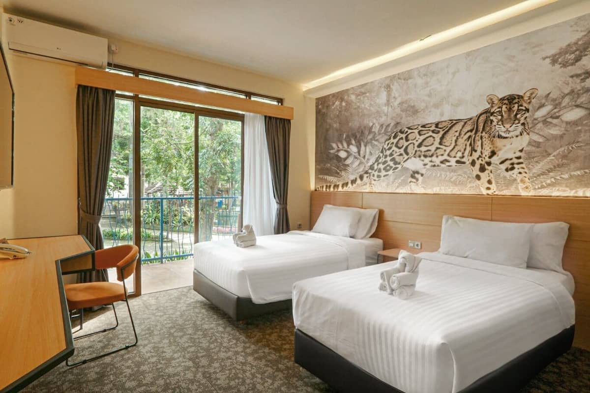 Une chambre d’hôtel avec deux lits, un bureau, une chaise et une grande fenêtre donnant sur un paysage verdoyant.