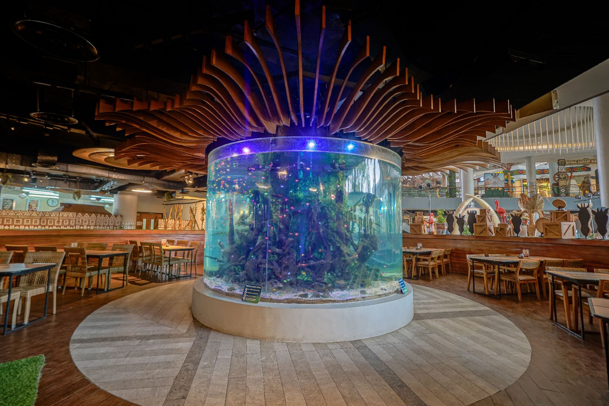 A restaurant with a central aquarium, wooden ceiling, and dining area with tables and chairs.