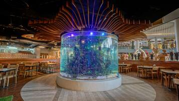 A restaurant with a central aquarium, wooden ceiling, and dining area with tables and chairs.