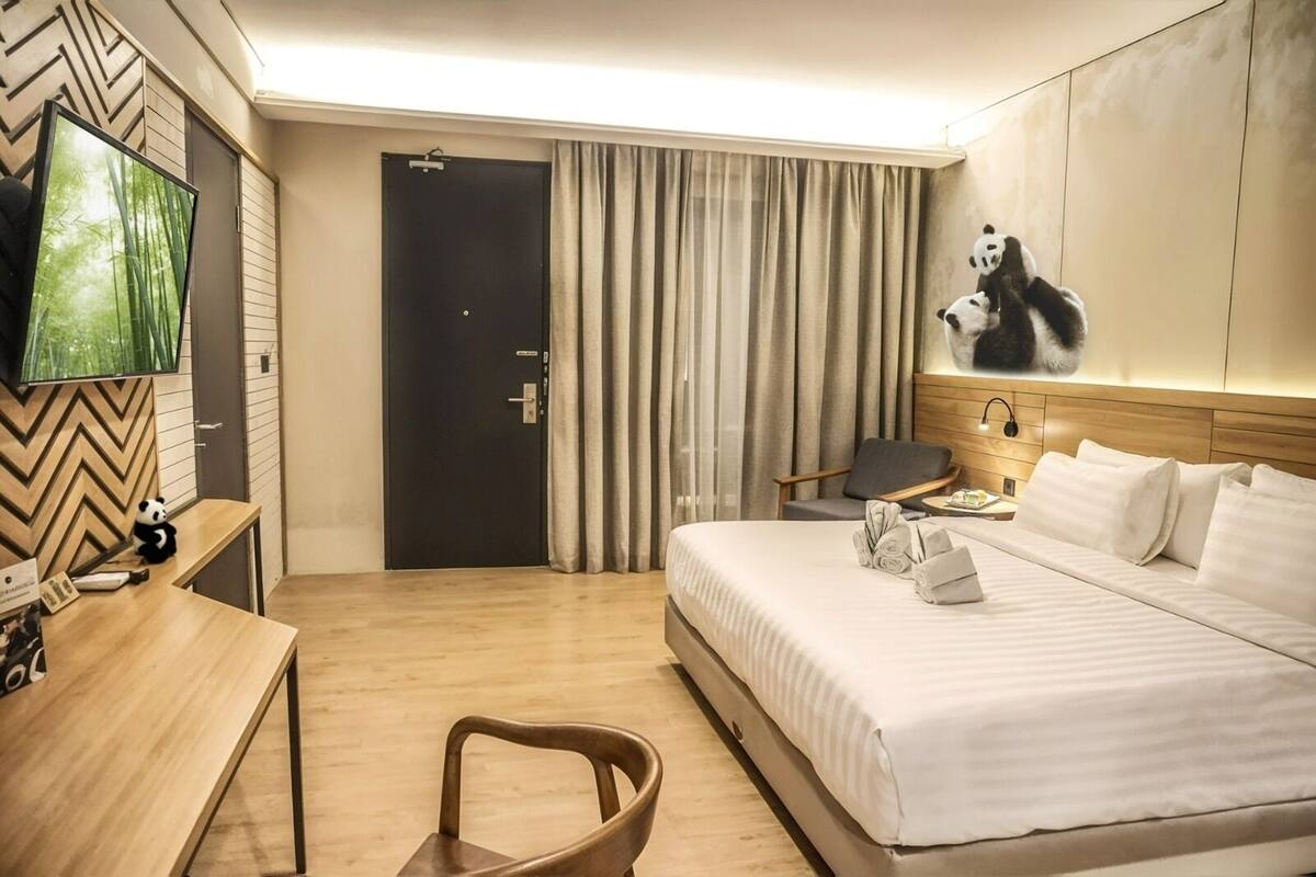 Une chambre d’hôtel avec un lit, un bureau, une chaise, une télévision et une porte.