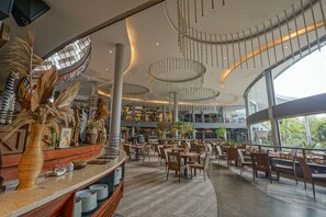 A spacious indoor area with high ceilings, modern lighting fixtures, and a variety of seating arrangements. - Royal Safari Garden Resort & Convention (Cisarua)