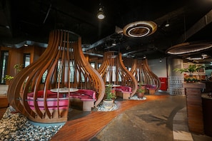 A modern interior with unique wooden structures, seating areas, and a bar. - Royal Safari Garden Resort & Convention (Cisarua)