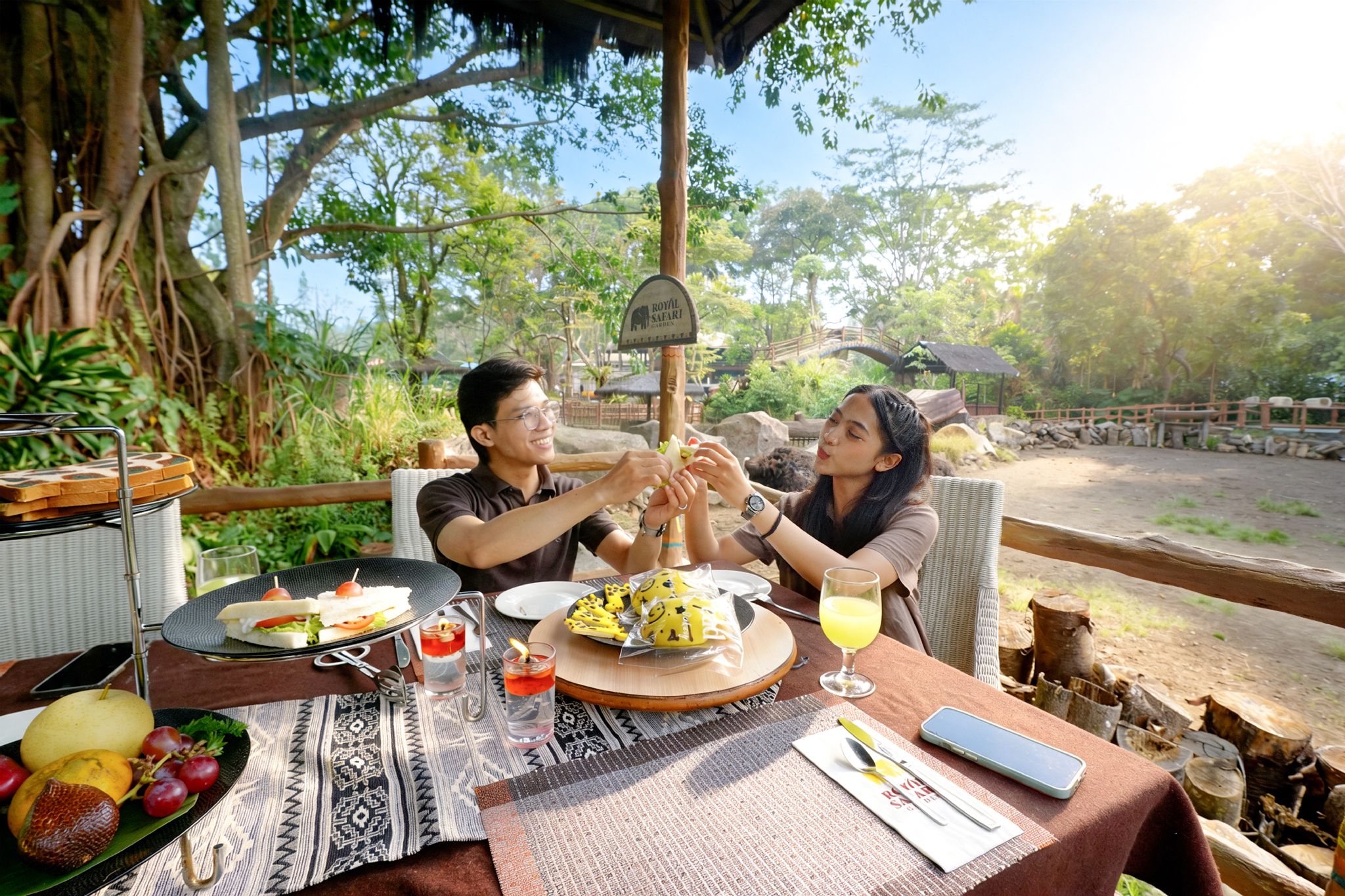 A dining table with food, drinks, and a sign indicating a safari garden.