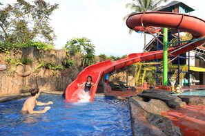 Un parque acuático con un tobogán rojo, una piscina y una zona de juegos.