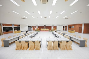 A conference room with multiple tables and chairs, a podium, and a large screen. - Royal Safari Garden Resort & Convention (Cisarua)