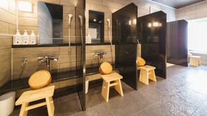 A modern bathroom with wooden paneling, a black vanity, a glass shower enclosure, and wooden stools. - Super Hotel Shinagawa Aomonoyokocho (Tokyo)