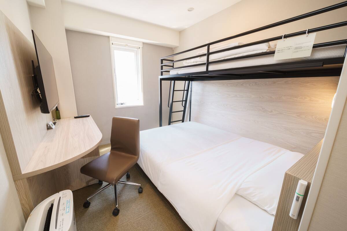 A bunk bed room with a desk, chair, and a small table.